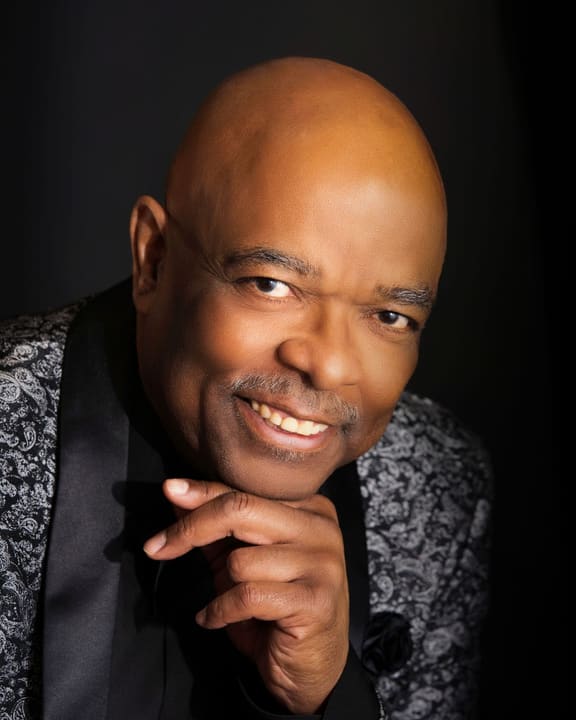 Portrait of Sheldon Price smiling, chin resting on his hand