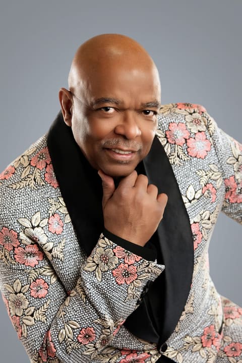 Sheldon Price in a floral jacket, hand at his chin